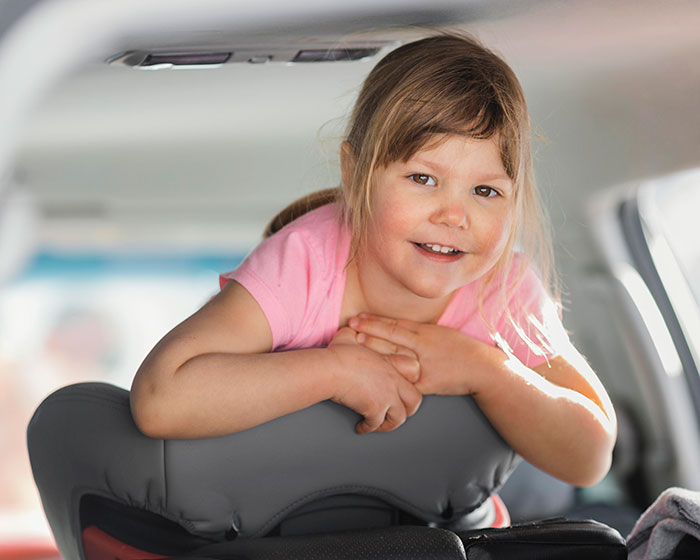 Smiling young girl leaning over car seat, representing a daughter with a husband ban on nanny Spanish lessons.