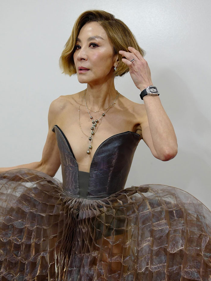 Michelle Yeoh wearing a wasp nest inspired outfit at a premiere, featuring a textured, layered dress and statement jewelry.