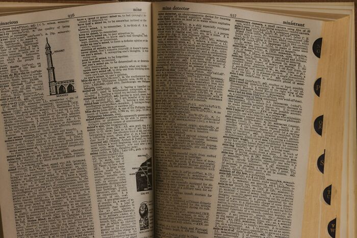 Open dictionary pages showing detailed etymology and definitions of common English words with illustrations.