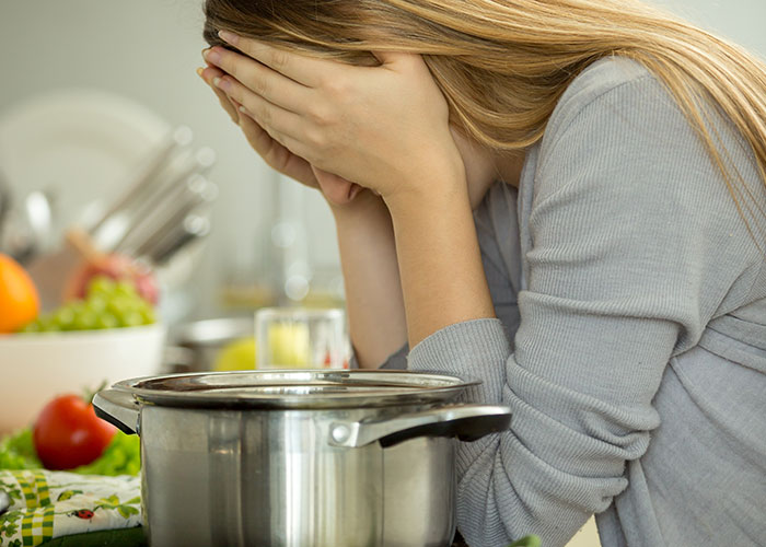 Woman covering her face with hands in kitchen, feeling stressed after a long 12-hour shift before Thanksgiving dinner preparation. Woman covering her face with hands in kitchen, feeling stressed after a long 12-hour shift before Thanksgiving dinner preparation.