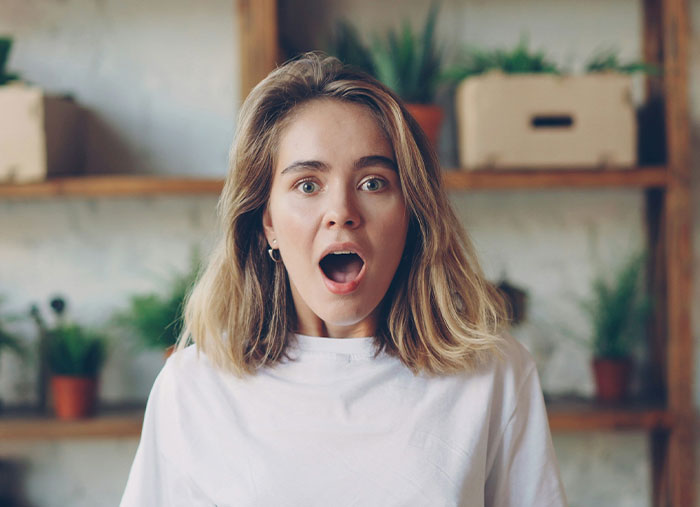 Bride shocked with mouth open, reacting to secret wedding invites and family image protection in a home setting.