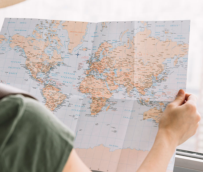 Person holding a world map, exploring mildly disturbing facts about geography and global locations in natural light.