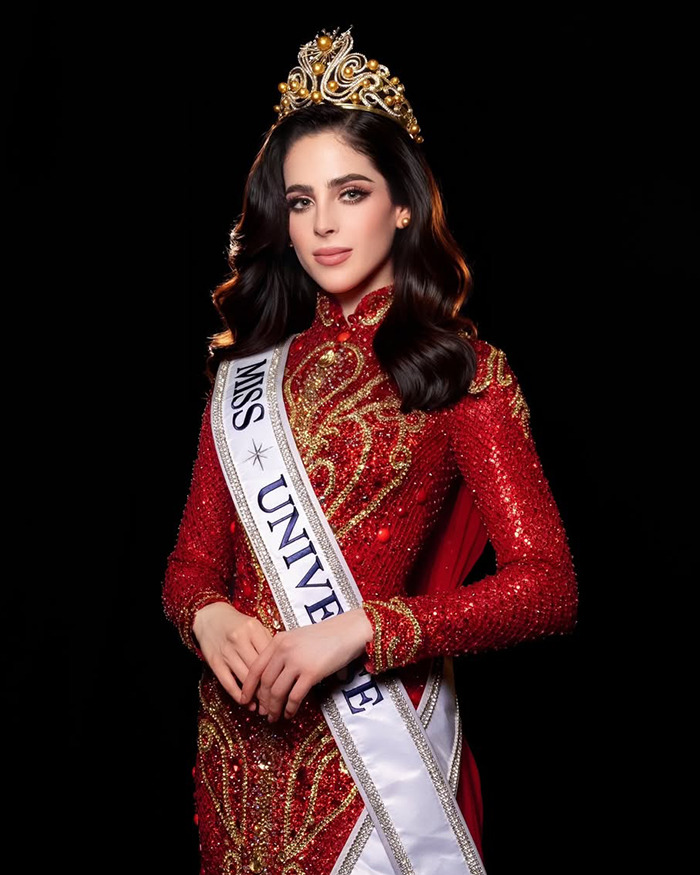 Miss Universe 2025 winner wearing crown and red embellished gown, amid backlash over victim narrative in her speech and victory.