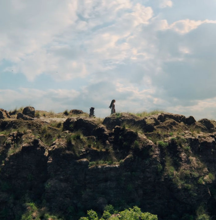 A person walks alone on rocky terrain under a cloudy sky, related to Disney live-action Moana appearance changes.