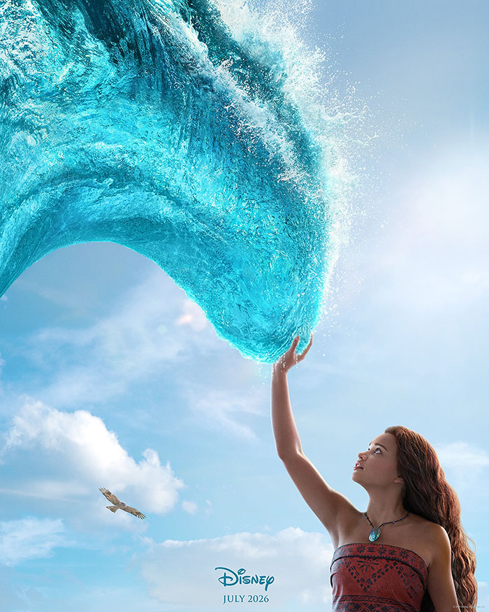 Live-action Moana character interacts with a large water wave forming above her against a bright sky.