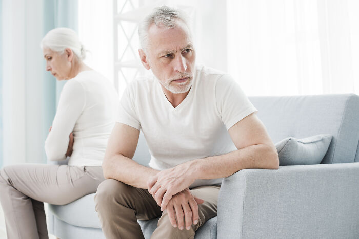 Older man and woman sitting apart on a couch looking upset, illustrating father-in-law treats DIL like dirt conflict.