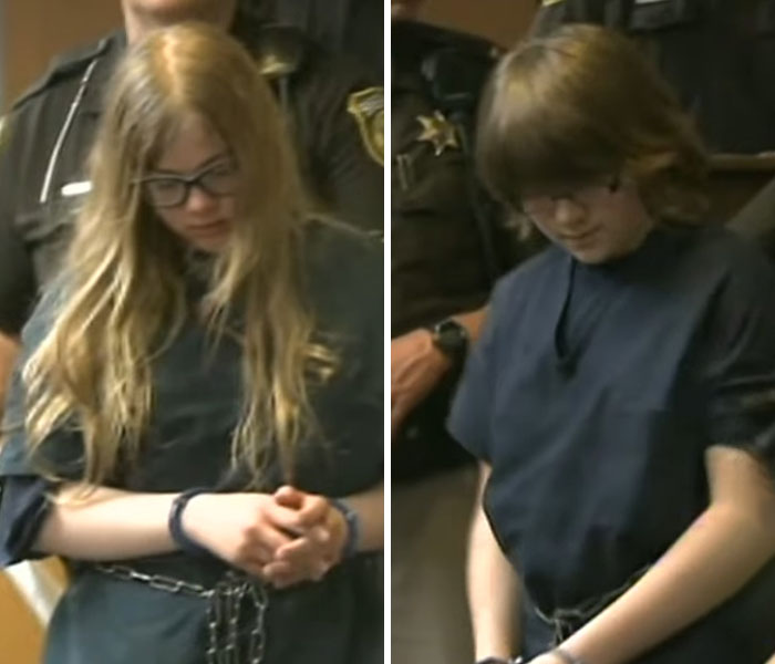Two Slender Man attacker suspects in handcuffs wearing dark prison uniforms during court appearance with police officers nearby Two Slender Man attacker suspects in handcuffs wearing dark prison uniforms during court appearance with police officers nearby