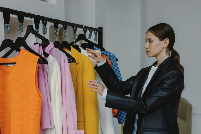 Woman in black jacket choosing colorful clothes from rack, illustrating inventive ways workers got away with breaking rules.