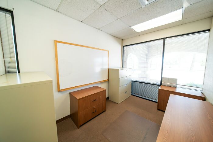 Empty office room with filing cabinets and a whiteboard, illustrating inventive ways workers broke rules.