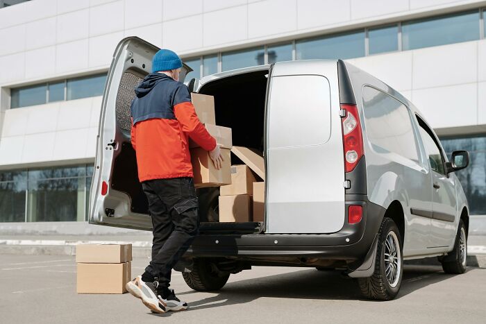 Worker unloading boxes from a van, showcasing inventive ways workers got away with breaking rules in a delivery setting.