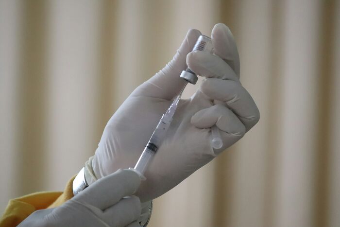 Doctor wearing gloves preparing a syringe with vaccine, illustrating eerie moments patients said that haunt doctors today.