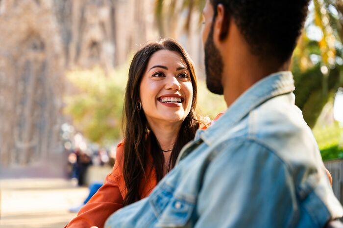 Young woman smiling and talking to a man outdoors, illustrating moments when people fell for scams and their impact.