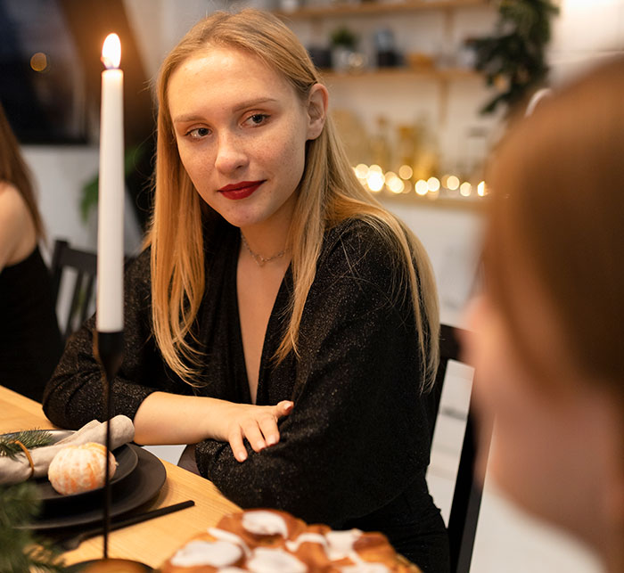 Young woman at Thanksgiving dinner looking thoughtful, reflecting on what her sister-in-law thinks about her.