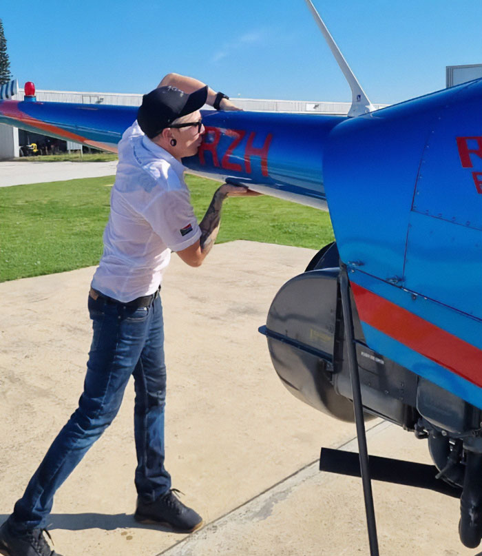 Man inspecting blue helicopter outdoors in bright daylight, related to celebrity chef tragic accident news.