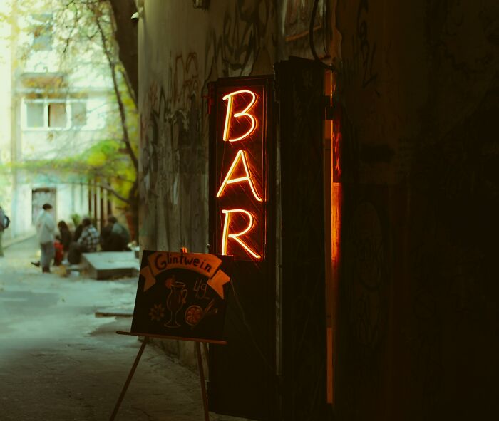 Neon bar sign glowing in a dark alley, symbolizing subtle signs that indicate they’re cheating in relationships.