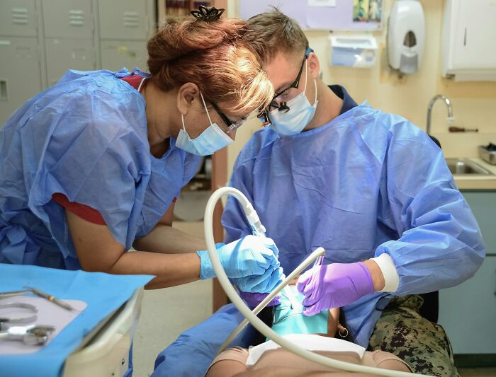 Two dentists wearing masks and gloves performing a dental procedure revealing wildest patient horror stories.