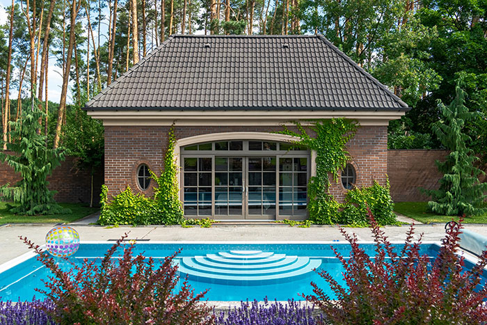 Backyard pool and brick house surrounded by trees in a neighbor&rsquo;s yard where kids used without asking.