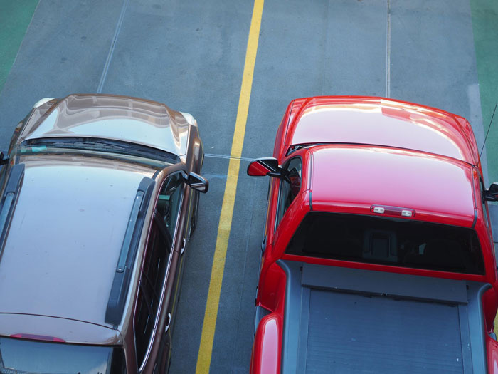 Improperly parked cars in a parking lot, illustrating male Karen refusing to park his car right despite neighbor's warning.