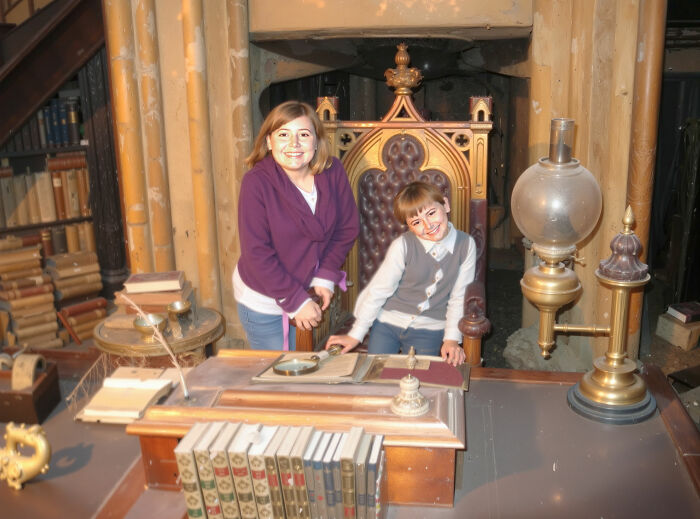 Two children pose smiling at a vintage desk surrounded by books and antique items, reflecting nepo babies insider experiences.