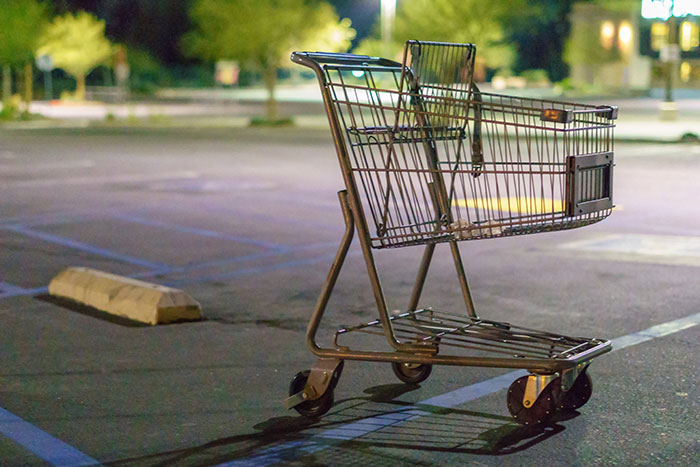 Empty shopping cart abandoned in a dimly lit parking lot, illustrating unusual moments shared by gas station workers.