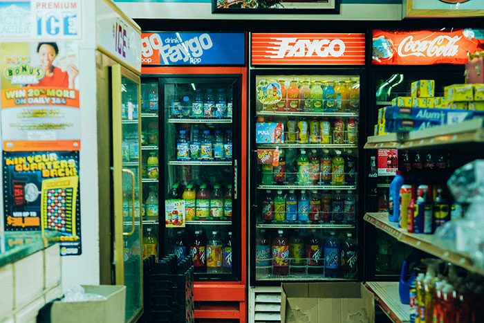 Gas station coolers stocked with beverages and snacks, showcasing a typical convenience store setup inside.