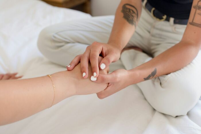 Person massaging foot of another on bed, illustrating family care and support in golden child stories context.