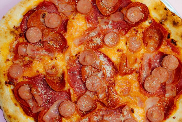 Pizza topped with pepperoni, sausage, and cheese, illustrating workers share unprofessional things done during breaks.