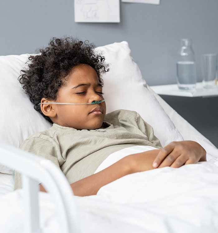 Young boy in hospital bed with nasal oxygen tube, representing coma survivors sharing their stories and recovery experiences.