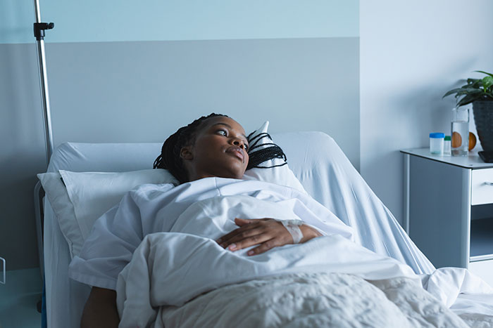 Young woman in hospital bed recovering, representing coma survivors sharing their stories and experiences.