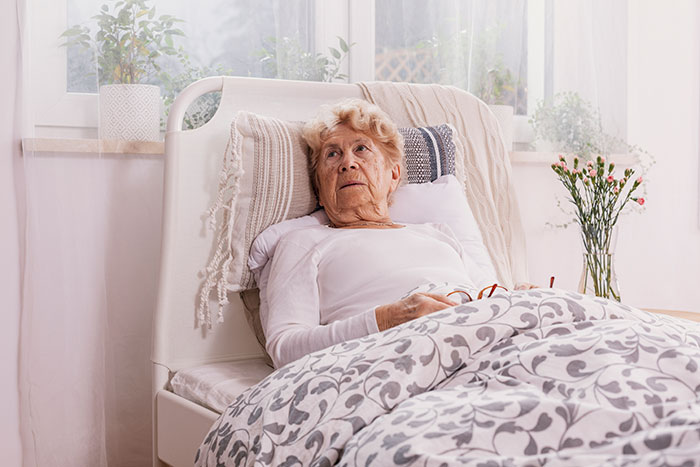 Elderly woman lying in bed recovering, representing coma survivors sharing their stories of survival and recovery.