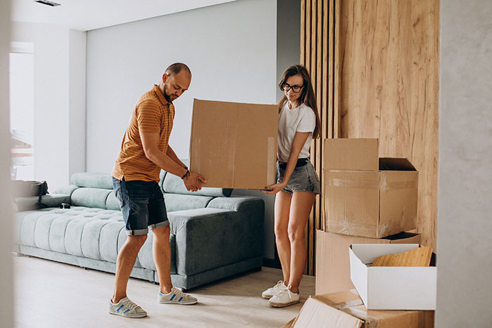 Couple carrying moving boxes in a modern apartment, symbolizing people who walked away from old lives to start new ones.