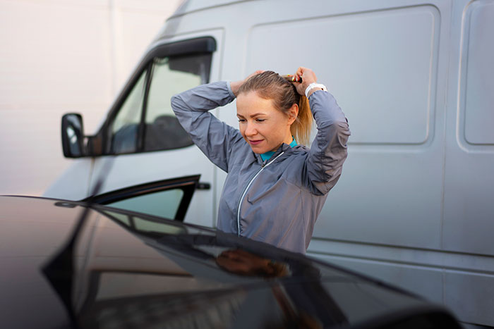 Young woman tying hair near a van, symbolizing people who walked away from their old lives and started new ones.
