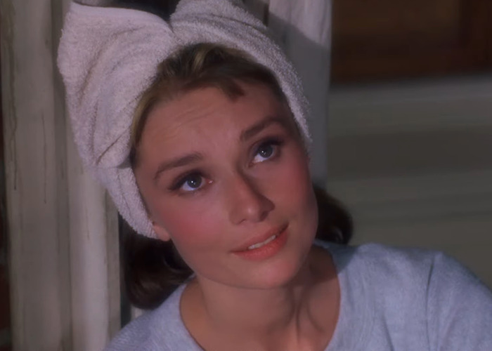 Audrey Hepburn with a towel wrapped on her head, showing natural aging in a classic film scene.
