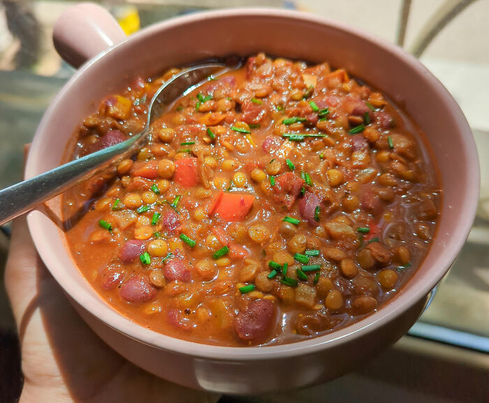 Bowl of hearty lentil and bean stew garnished with fresh herbs, showcasing kitchen tips and tricks for cooking skills.