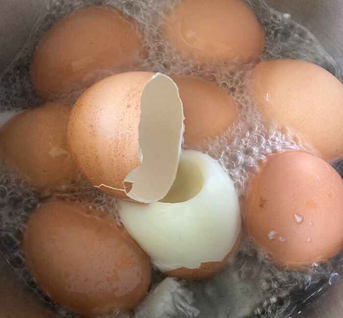 Boiling eggs with shells cracking in hot water, demonstrating kitchen tips and tricks to upgrade cooking skills.