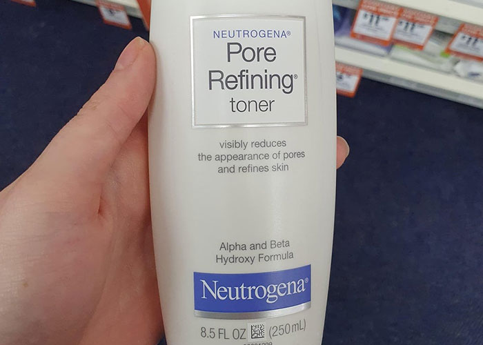 Hand holding discontinued Neutrogena Pore Refining toner bottle, a product people are upset about.
