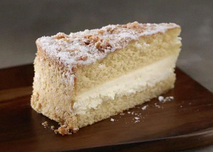 Slice of discontinued cream-filled cake on a wooden board, highlighting popular foods people are upset about losing.