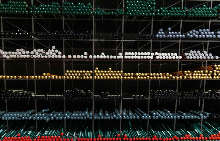 Rows of colored drumsticks arranged by color in a grid rack, challenging viewers to spot the connection.