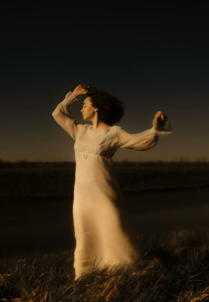 Woman in a flowing white dress standing in a field at dusk, evoking haunting things truckers have seen on the road at night.