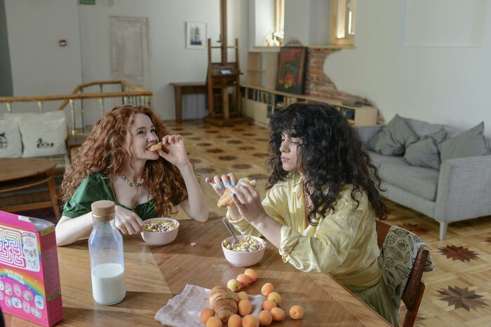 Two women enjoying breakfast together in a cozy room, sharing moments of realizing compulsory things are optional.
