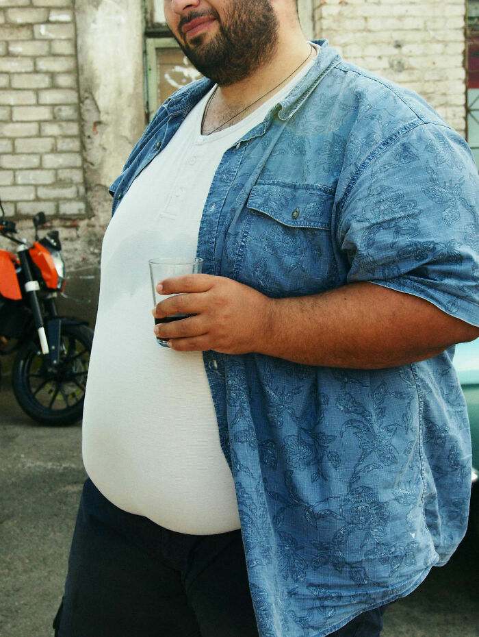 Man in casual blue shirt and white t-shirt holding a glass, related to nurses of psych wards intense stories.