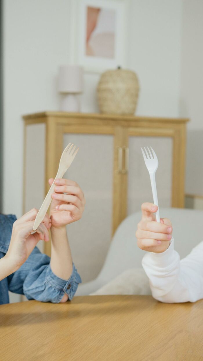 Two people holding plastic forks in a casual setting, capturing bizarre moments that make people wonder about sanity.