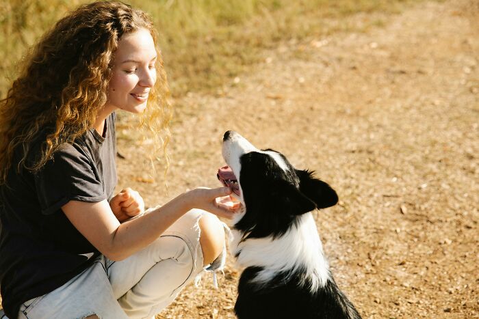Young woman interacting with her black and white dog outdoors, showcasing relatable moments of everyday life.