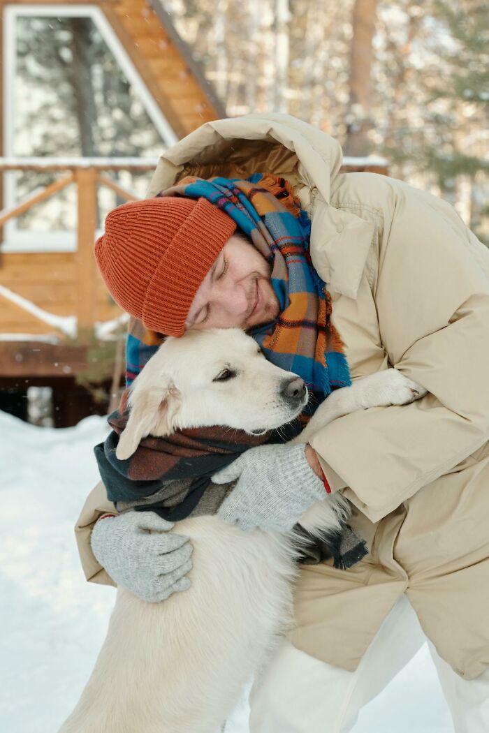 Man in winter clothes hugging a dog outdoors, unrelated to garbage men or horrifying finds on the job.