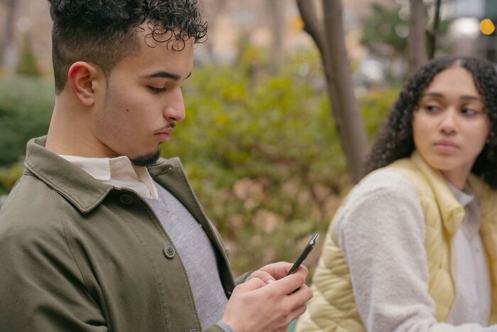 A tense couple outdoors showing signs of toxic relationship traits with distant and distracted body language.