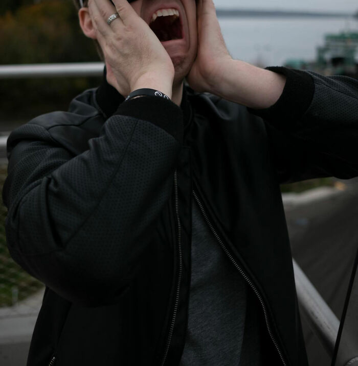 Man in black jacket holding face in shock outdoors, illustrating garbage men finding something horrifying on the job.
