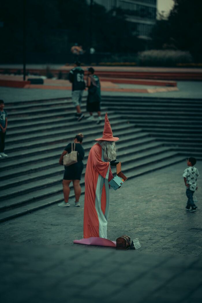 Street performer dressed as a wizard in a bizarre moment capturing the surreal and unusual side of public spaces.