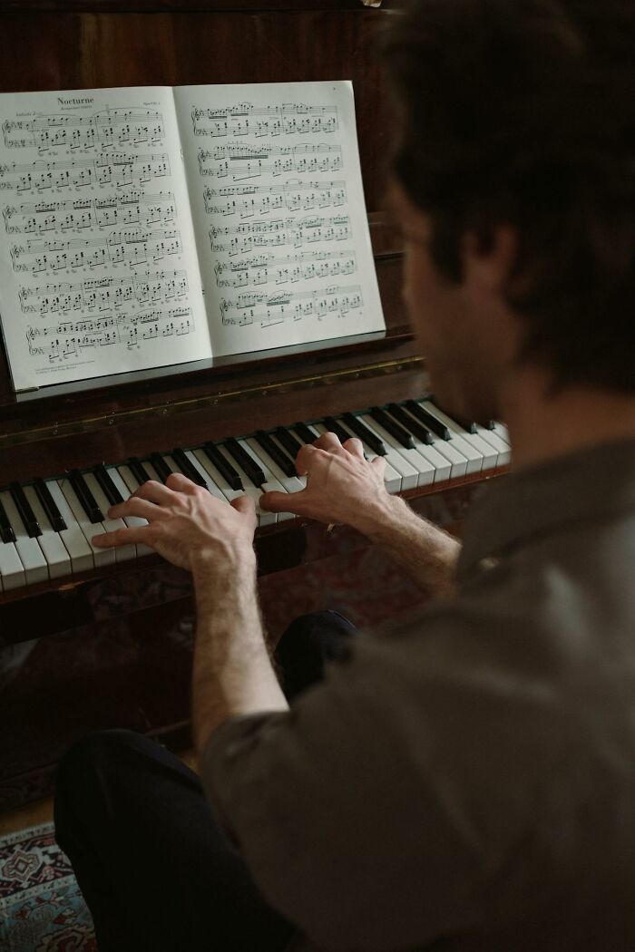 Person playing piano with sheet music, symbolizing calm and reflection in psych ward nurses' intense stories.