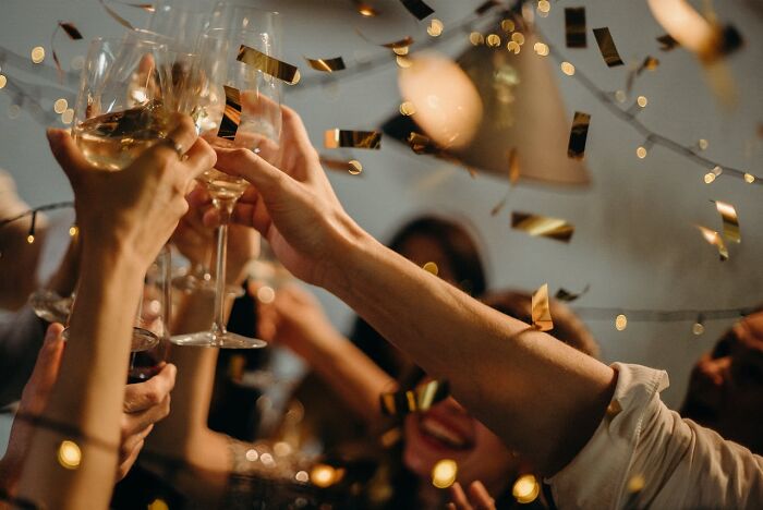People raising glasses in celebration with confetti falling, representing childhood habits that were anything but normal.