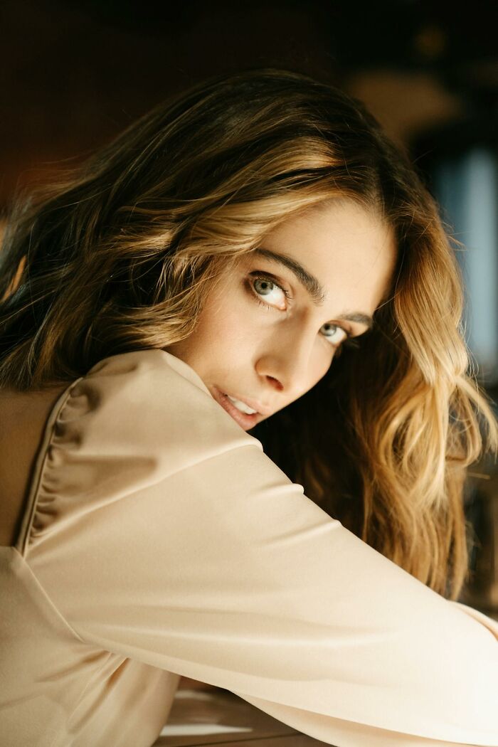 Young woman with wavy hair, wearing a beige top, looking contemplative, reflecting harsh truths about marriage.